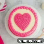 Overhead view of a perfectly decorated pink velvet cake with a beautiful pink frosted heart design on top.