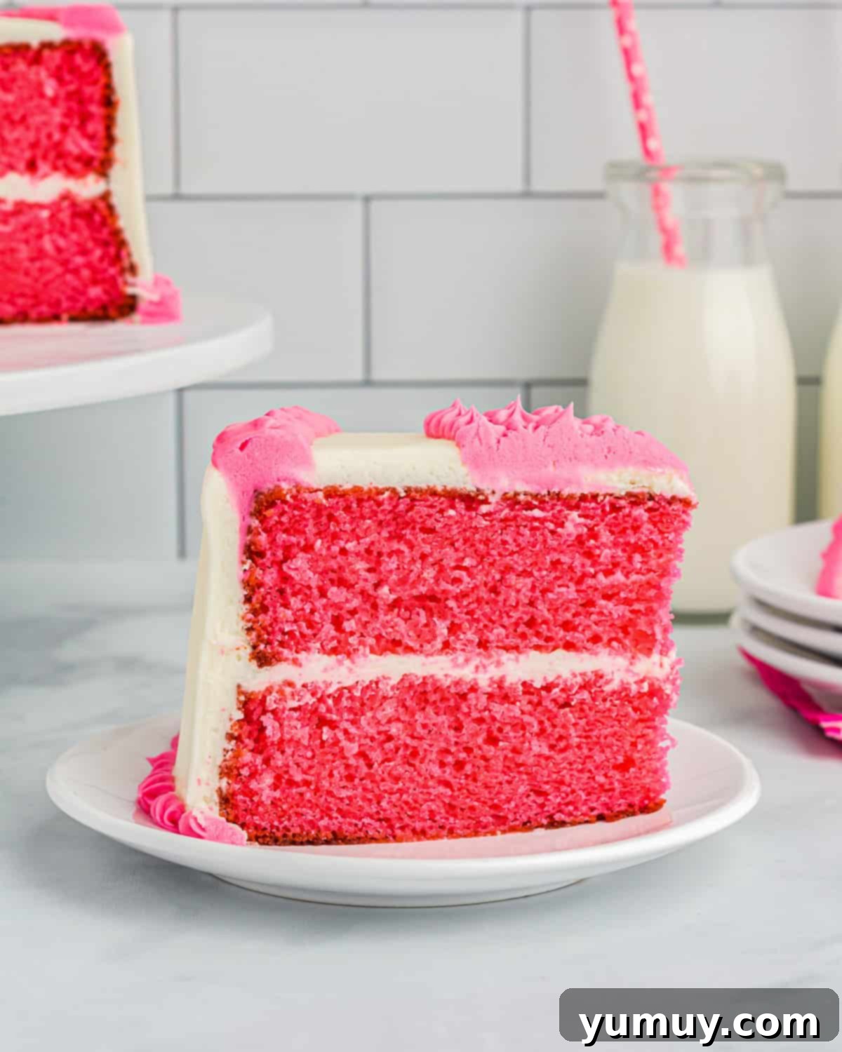 A captivating side view of a perfectly frosted slice of pink velvet cake, highlighting its moist layers and creamy texture.