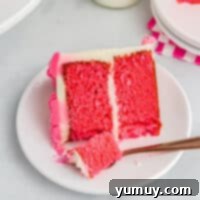 A partially eaten slice of pink velvet cake on a white plate with a fork, emphasizing its delightful appearance and texture.