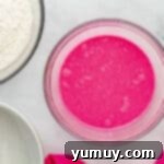 Neon pink liquid in a glass bowl, showcasing the vibrant color of the wet ingredients.