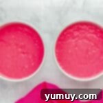 Pink velvet cake batter evenly distributed in two round cake pans, ready for baking.
