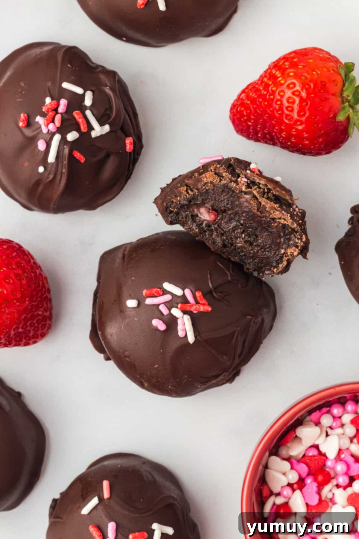 Rows of perfectly coated strawberry truffles resting on parchment paper, glistening and ready to set.
