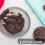 Mixing crushed Oreos, cream cheese, strawberries, frosting, and Jell-O for truffles in a bowl.