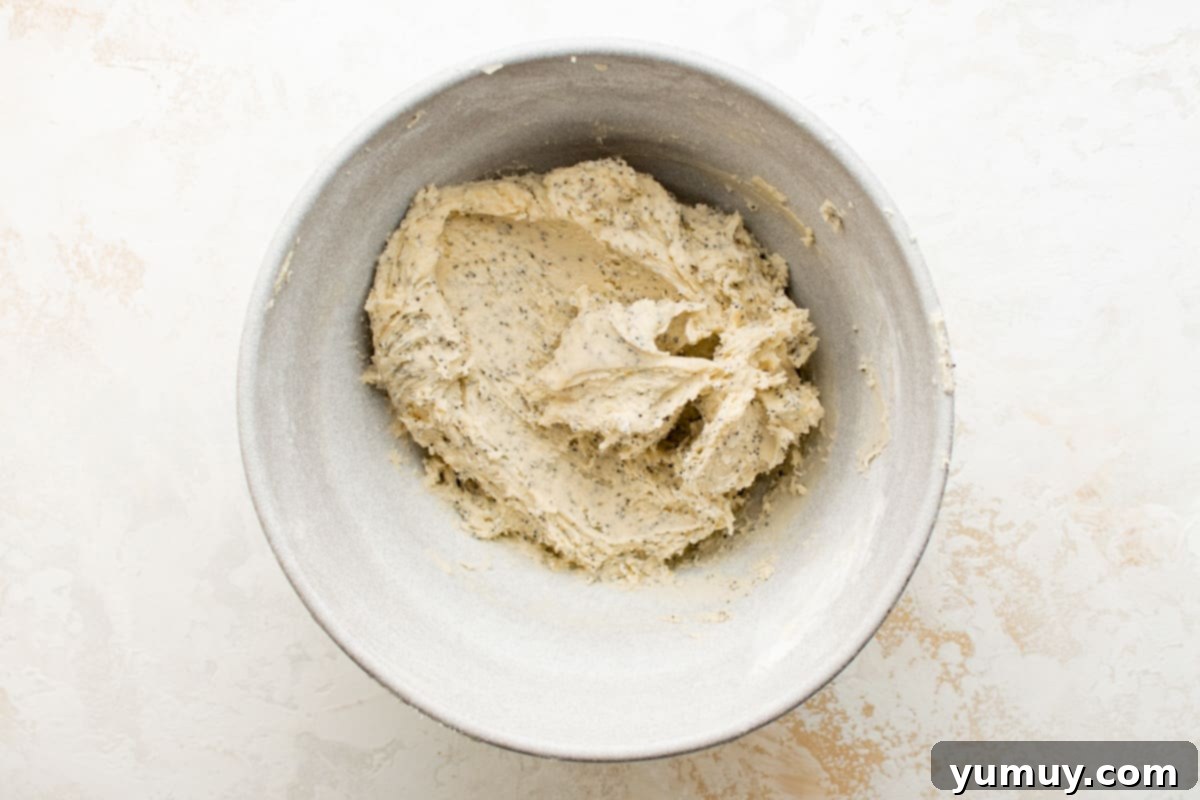 Tangy Lemon Curd Delights 12 A bowl filled with a perfectly mixed, soft, and fragrant lemon cookie dough, ready for shaping, resting on a white surface.