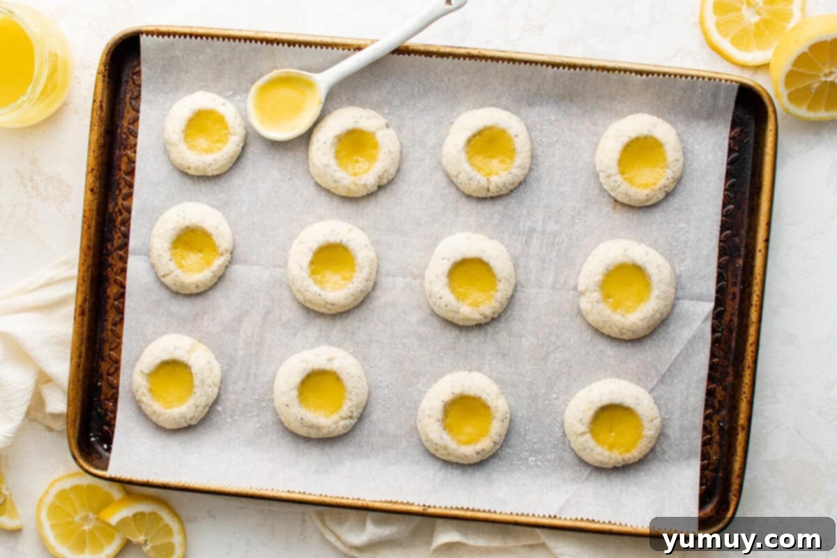 Tangy Lemon Curd Delights 15 Freshly baked lemon curd cookies with beautiful golden edges, cooling on a baking sheet, with a spoon nearby, inviting a taste.