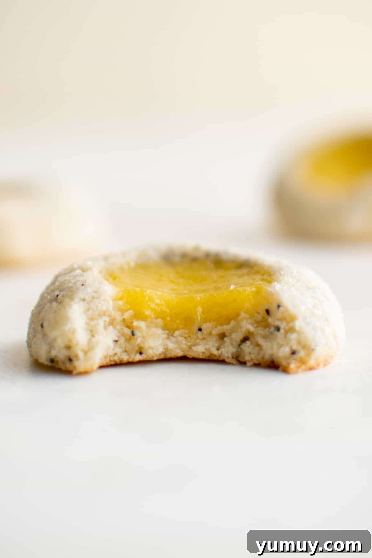 Tangy Lemon Curd Delights 3 Close-up of vibrant thumbprint cookies filled with luscious lemon curd, beautifully arranged on a white surface, ready to be enjoyed.