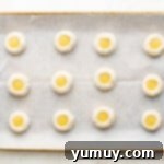 Tangy Lemon Curd Delights 8 Thumbprint cookies on a baking sheet, each divot precisely filled with vibrant lemon curd, awaiting their bake.