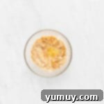 The crushed vanilla wafer crust pressed firmly into the base of a springform pan, creating an even layer.