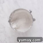 Perfectly whipped marshmallow meringue in a stainless steel mixing bowl, showing stiff peaks.