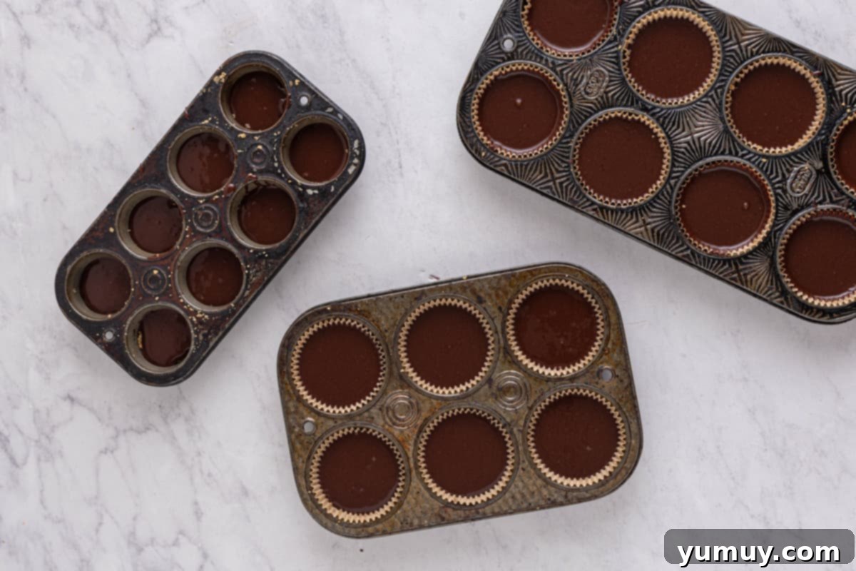 Cupcake tins with liners, each filled ¾ full with rich chocolate cupcake batter.