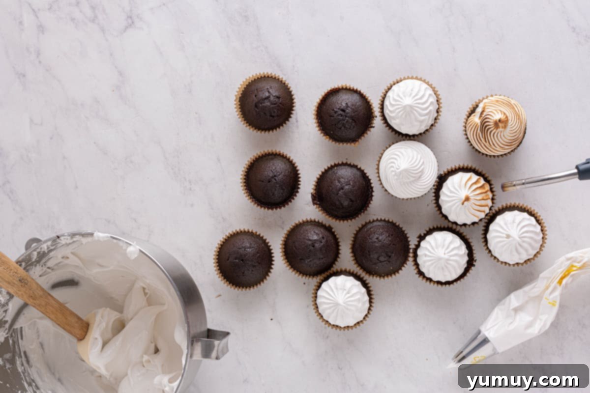A kitchen torch delicately toasting the marshmallow meringue on top of chocolate cupcakes, creating a golden-brown finish.