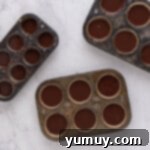 Cupcake tins with liners, each filled ¾ full with rich chocolate cupcake batter.