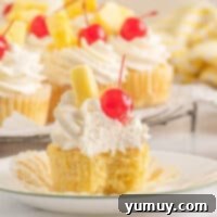 pineapple cupcakes with whipped cream and cherries.