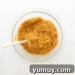 Luscious Strawberry Cheesecake Bars 5 Strawberry cheesecake bars crust ingredients in a glass bowl with a spoon, ready to be mixed.