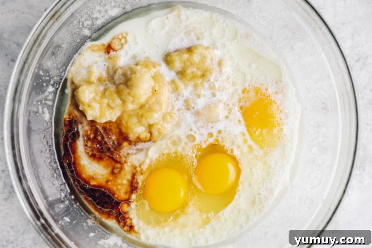 overhead view of wet ingredients for banana cake in a glass bowl.