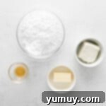 Overhead view of softened butter and cream cheese in individual bowls, awaiting use for frosting.