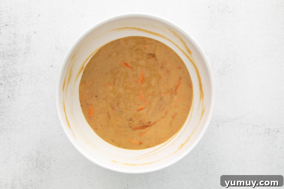 A bowl of rich, spiced carrot cupcake batter ready for baking, showcasing its smooth texture.