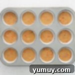 Cupcake batter filled into a cupcake tin with paper liners, ready for baking.