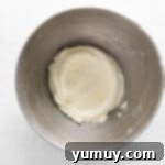 Smooth, fluffy cream cheese frosting in a stainless steel mixing bowl, ready for coloring.