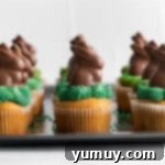 A baking tray filled with freshly frosted Easter bunny cupcakes, each adorned with a cute chocolate bunny.