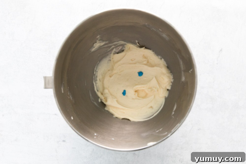 frosting for easter cupcakes in a stainless mixing bowl with 2 drops of blue food coloring on top