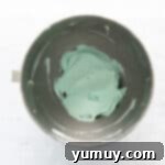 overhead view of robin egg blue frosting in a stainless mixing bowl.