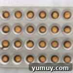 Peanut butter cups in a muffin tin, showing the layering process.