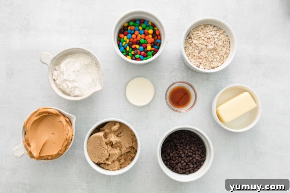 No-Bake Monster Cookie Dough 5 Bowls of prepped ingredients for peanut butter cookie dough laid out on a clean white background.