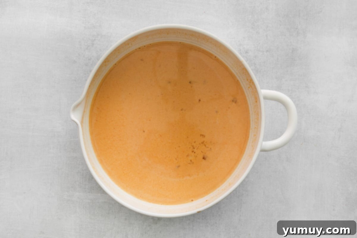 A bowl containing smooth, whisked wet ingredients for pumpkin pancakes.