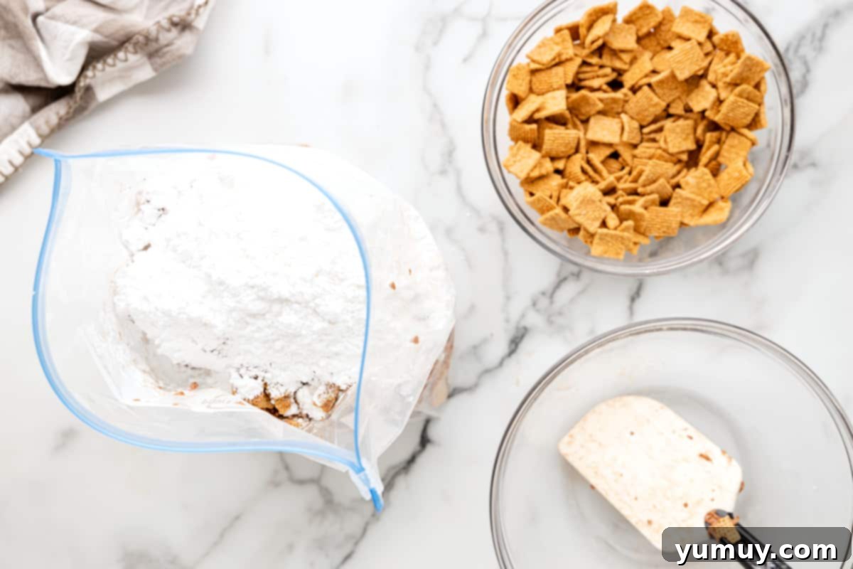 Campfire Crunch Bites 11 powdered sugar poured over s'mores puppy chow in a ziplock bag.