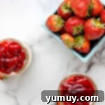 Finished cheesecake jars, each generously topped with bright red strawberry pie filling.