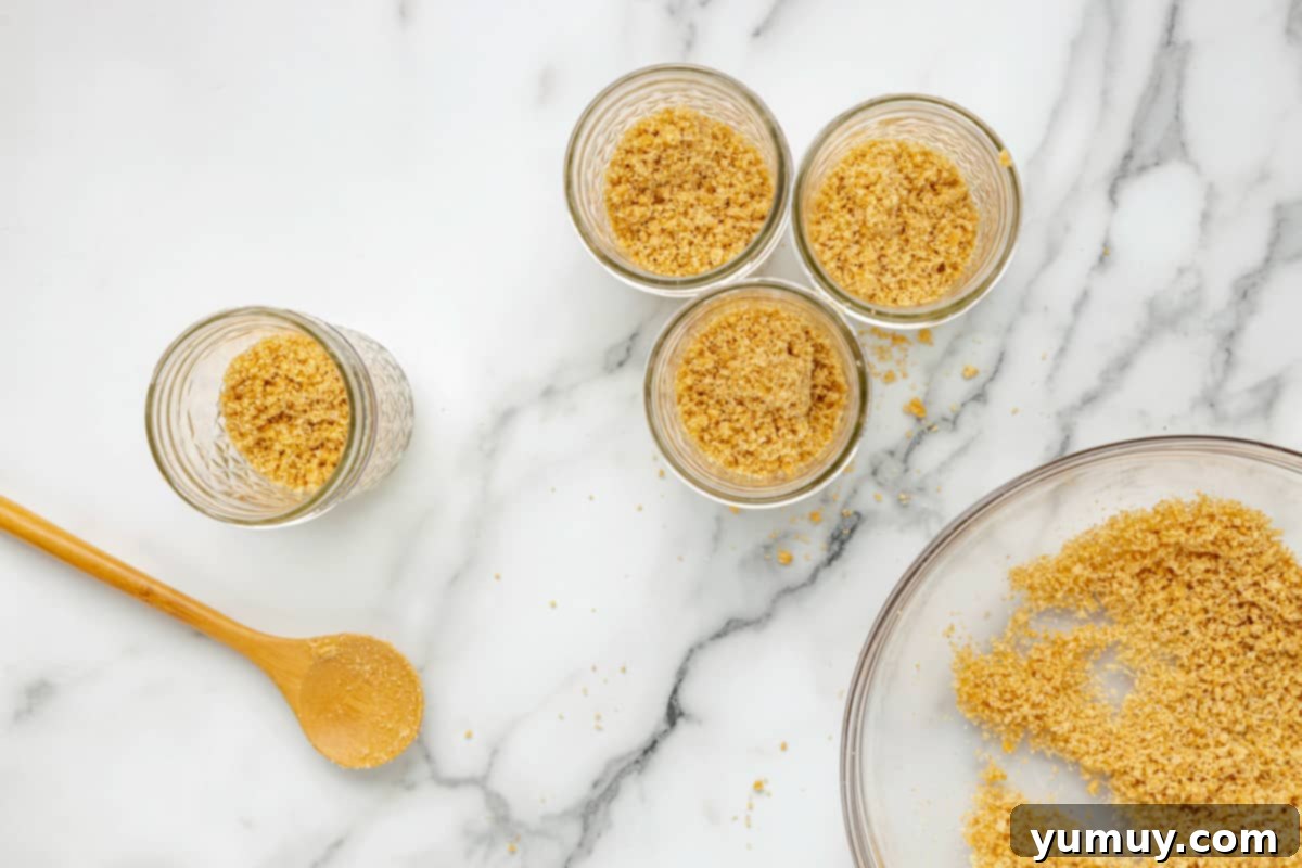 A collection of glass jars, each containing a perfectly pressed brown graham cracker crust layer.