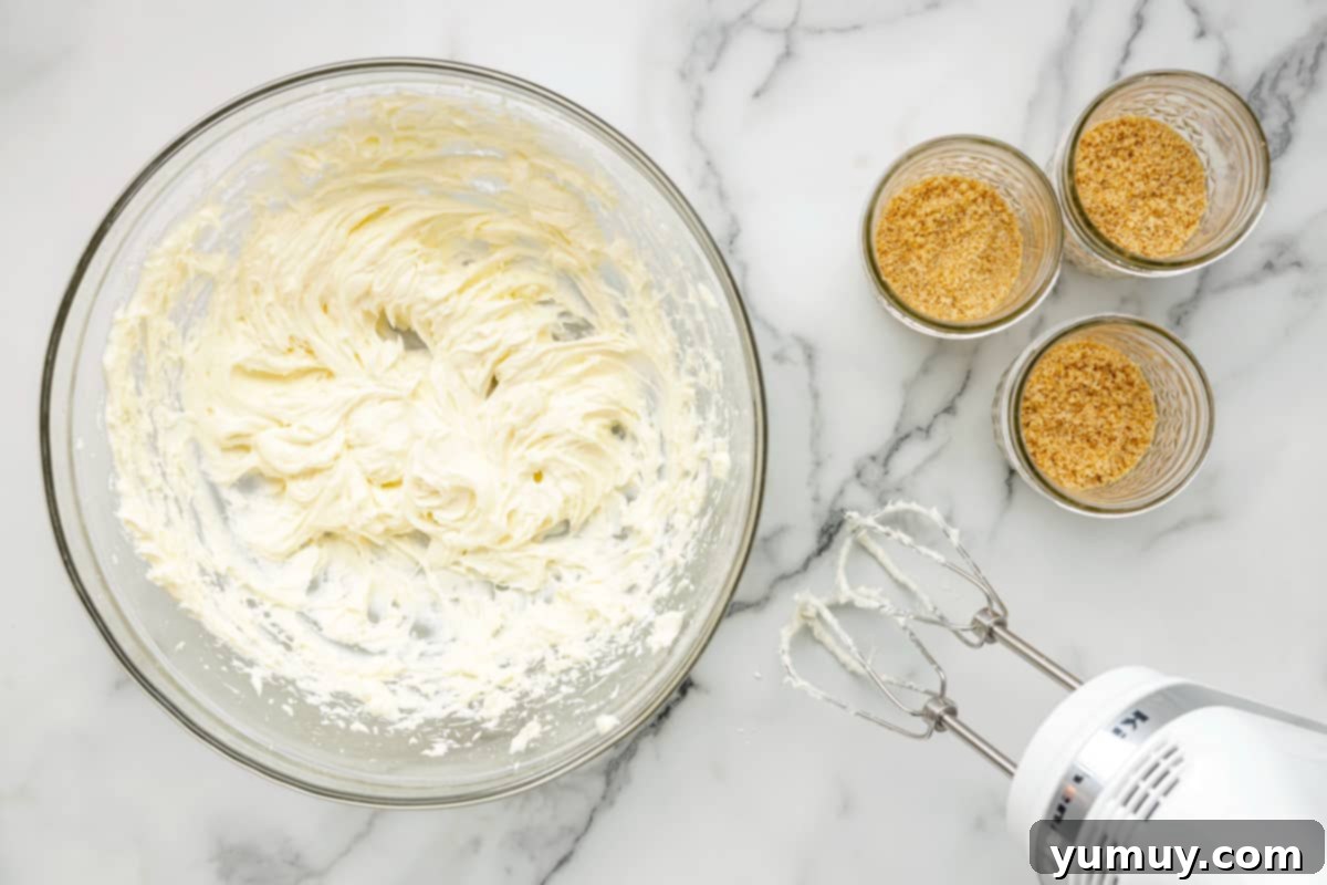A mixer whisking heavy cream in a bowl, demonstrating the formation of soft peaks for the cheesecake filling.