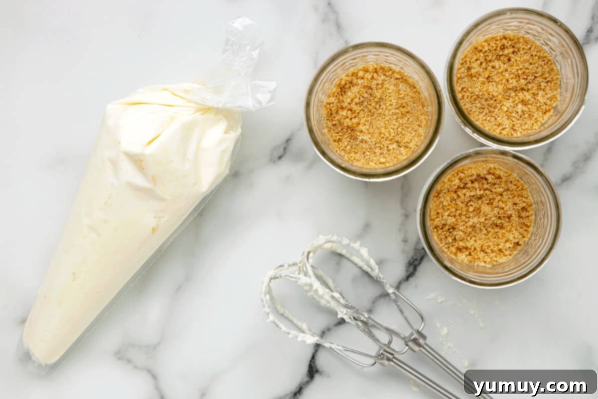 The smooth cheesecake filling being piped from a bag into glass jars, creating a beautiful layered effect.