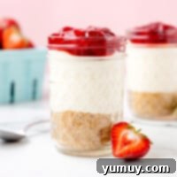 Two mason jars showcasing beautifully layered strawberry cheesecake, ready for serving.