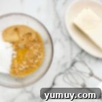 A bowl containing graham cracker crumbs, sugar, and melted butter, ready to be mixed for the crust.