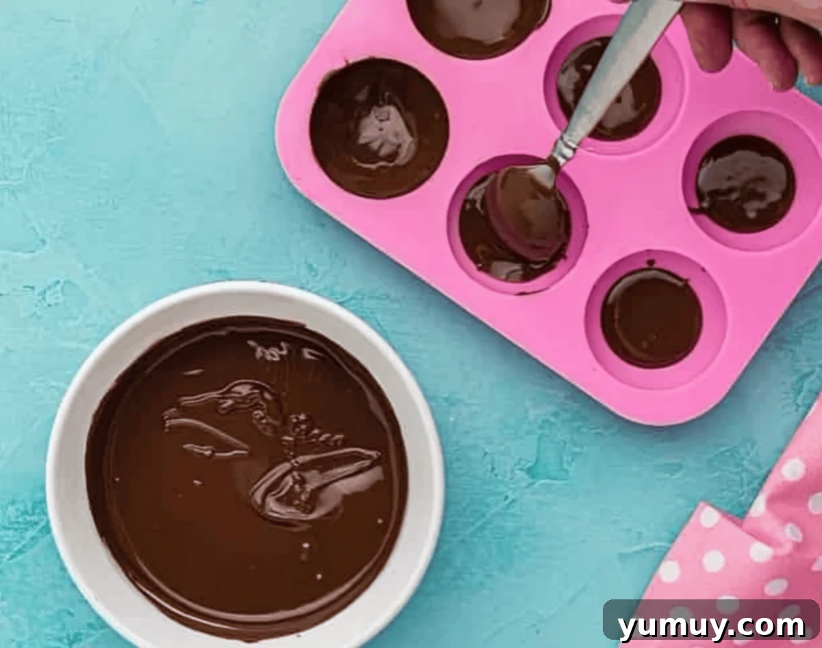 brushing melted chocolate in a half-sphere mold.