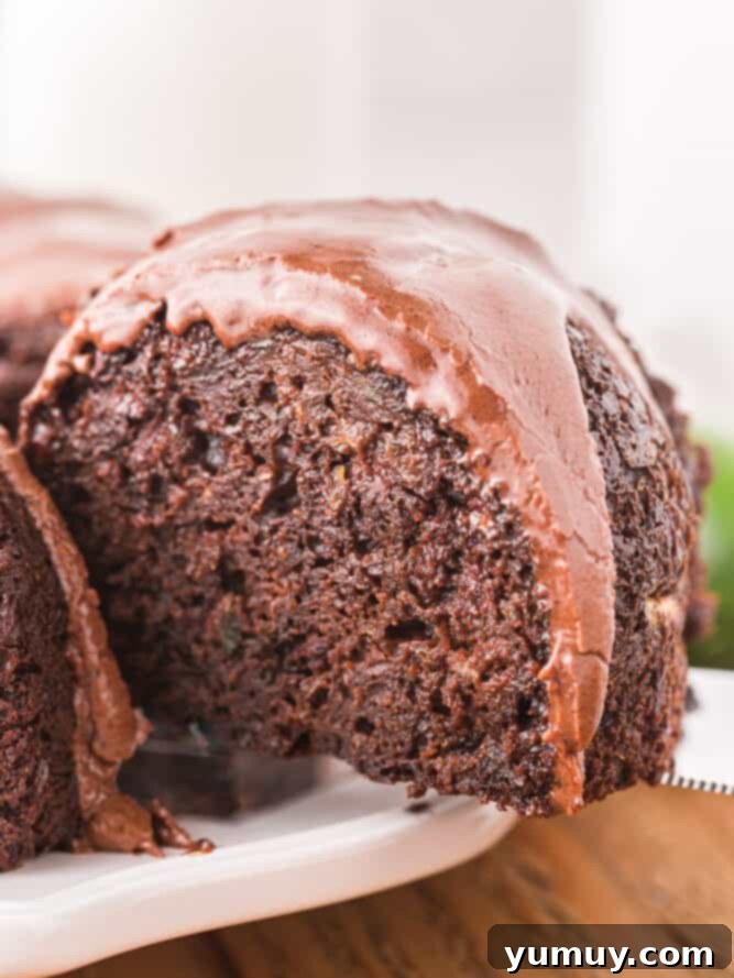 Luscious Chocolate Zucchini Bundt 2 A large slice being removed from a glistening chocolate zucchini bundt cake, showcasing its rich, moist interior.