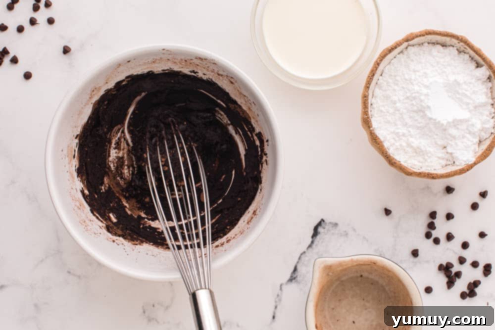 Luscious Chocolate Zucchini Bundt 11 Butter and cocoa powder mixed together with a whisk in a white bowl, forming the glaze base.