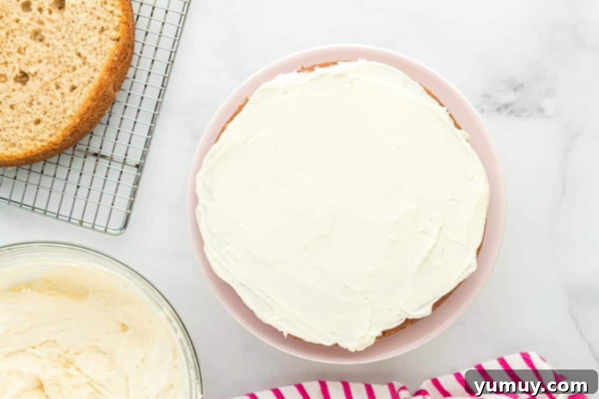 frosting coating a layer of donut cake on a cake stand.