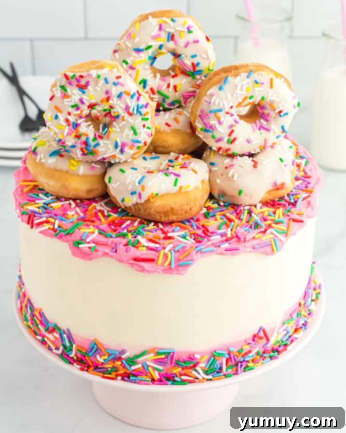 three-quarters view of frosted donut themed cake topped with mini donuts.