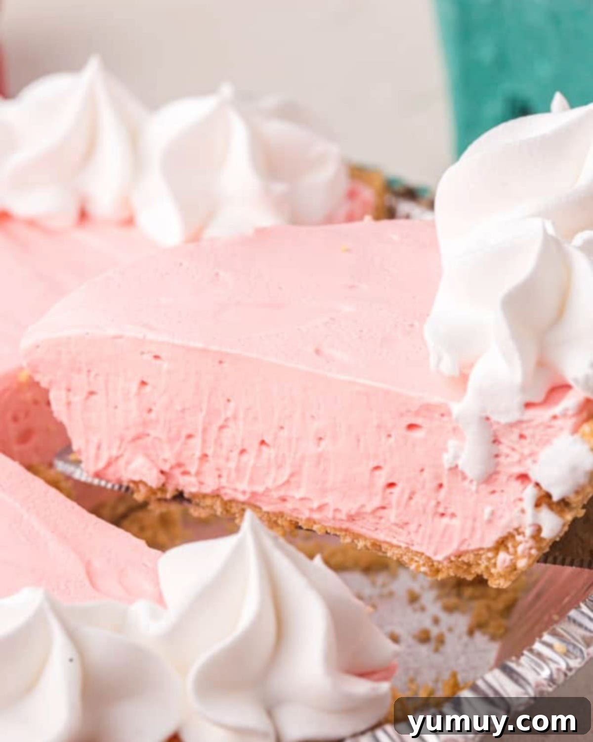 side view of a slice of kool aid pie being lifted from a disposable aluminum tray.
