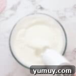 Airy Dream Cake 6 beating egg whites in a glass bowl with a hand mixer.