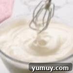 Airy Dream Cake 7 egg whites beaten to peaks in a glass bowl with beaters.