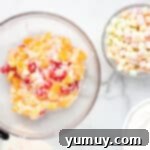 Mixed canned fruits in a glass bowl with yogurt and coconut flakes.