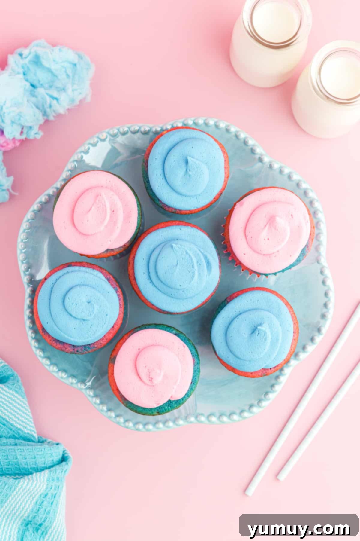 overhead view of 7 cotton candy cupcakes on a blue cake stand.