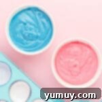 2 bowls of cotton candy cupcake batter, one colored blue and one colored pink.
