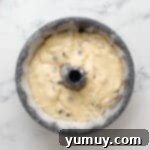 Bursting Blueberry Bundt 12 Blueberry bundt cake batter in a greased and floured bundt cake pan, ready for baking.