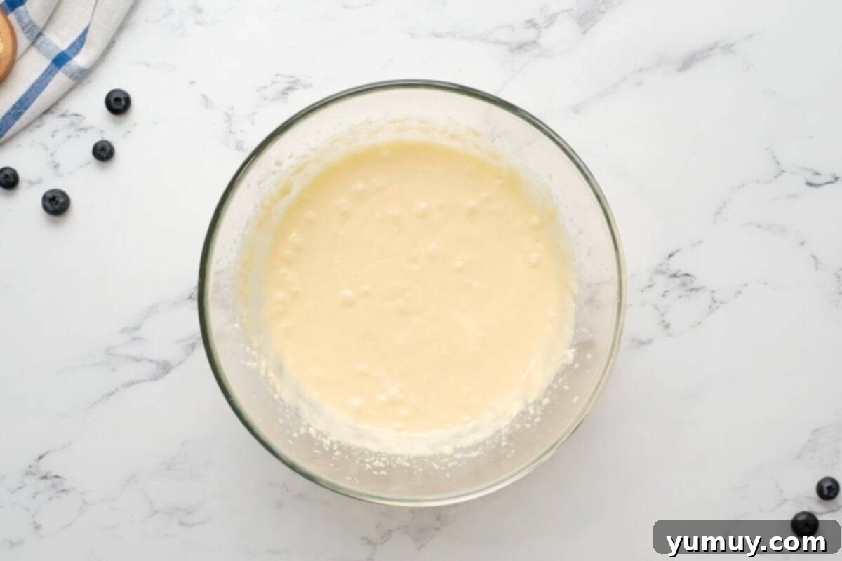 Bursting Blueberry Bundt 18 The wet ingredients for the blueberry bundt cake, including sour cream, being mixed in a glass bowl.