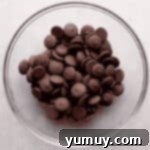 Magical Lucky Charms Hot Cocoa Bombs 5 Melted chocolate wafers in a glass bowl, ready for molding.